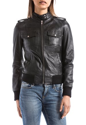 Giacca in pelle nera con zip frontale, due tasche sul petto, spalline sulle spalle e polsini e orlo a costine. Finitura testurizzata, design aderente.