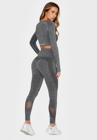 Gray athletic set featuring a long-sleeve crop top and high-waisted leggings with mesh accents. Made from stretchy, textured fabric.