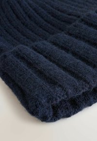 Granatowa, dziana czapka beanie o prążkowanej fakturze. Wykonana z miękkiej, puszystej przędzy, ma podwinięty rant i gładki, zaokrąglony kształt.