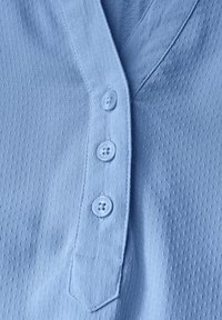Camicia azzurra a maniche corte con tessuto testurizzato, chiusura a bottoni frontale con tre bottoni abbinati e design del colletto classico.