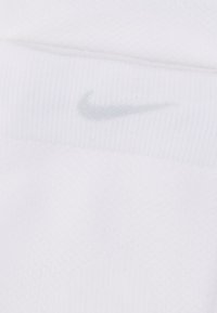 Λευκή κορδέλα κεφαλής Nike από υφασμάτινη υφή, με ανοιχτό γκρι κεντημένο λογότυπο swoosh στο μπροστινό μέρος.