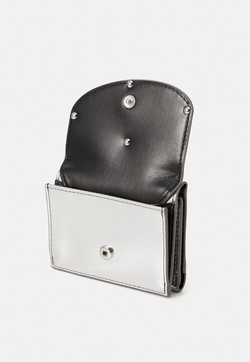 Schwarze Leder-Brieftasche mit einer silbernen metallischen Vorderseite. Verfügt über einen Druckknopfverschluss und dekorative silberne Nieten auf der runden Klappe. Insgesamt glatte Textur.