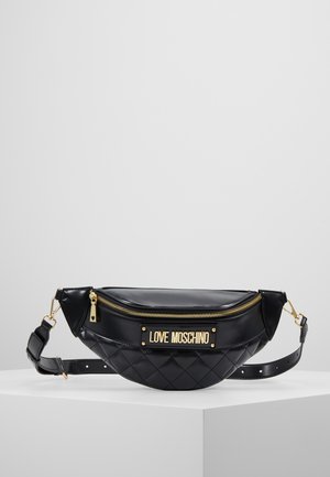 Riñonera Love Moschino negra acolchada con cremallera dorada y placa con logo, correa ajustable, expuesta sobre una plataforma blanca con fondo claro.