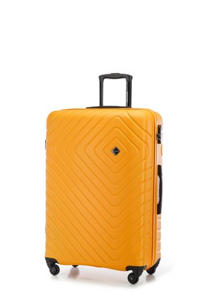 Żółta twarda walizka z ukośnymi żłobieniami, chowanym czarnym uchwytem i czterema czarnymi kółkami dla łatwego poruszania się. Posiada diamentowy emblemat.