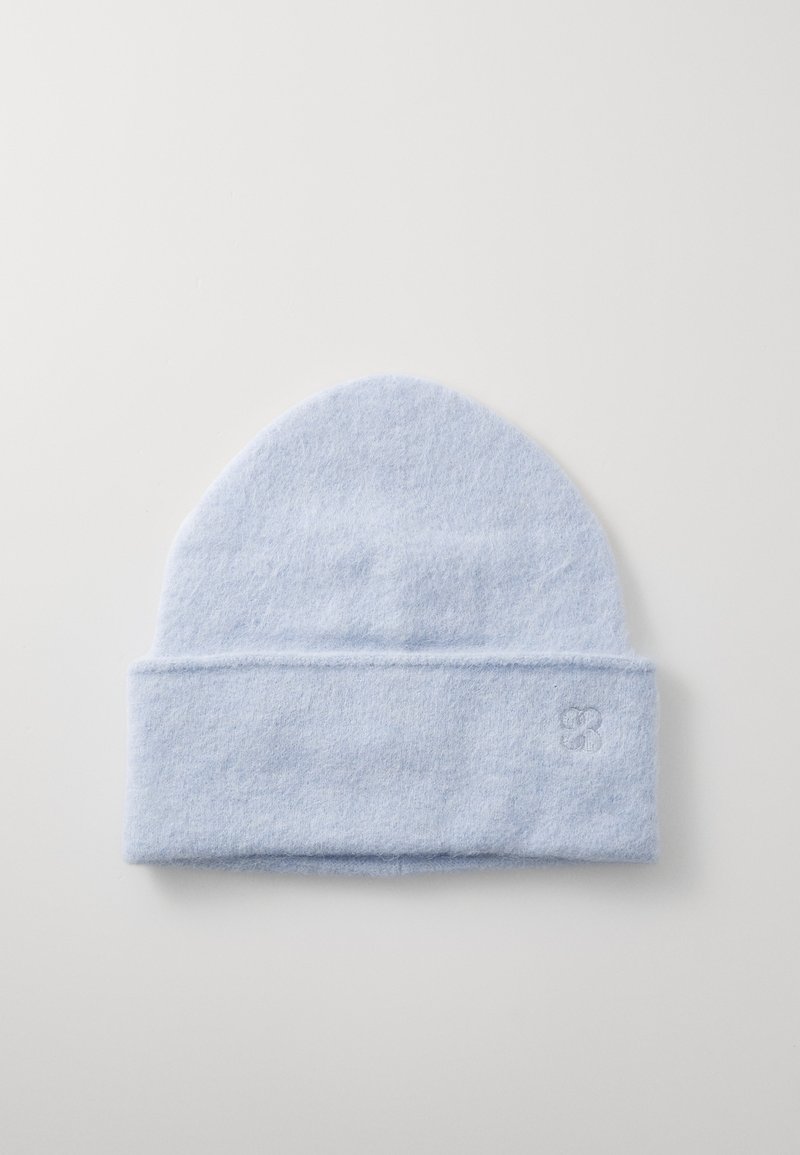 Gaiši zilā adītā cepure, izgatavota no maigas vilnas. Tai ir salocīts mala un diskrēta logo izšūšana sānos. Gluda tekstūra.