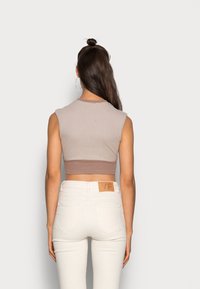 Camisola curta em bege claro com um design ajustado e mangas curtas; combinada com jeans brancos de cintura alta com bolsos traseiros.