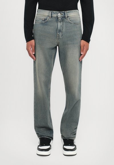 Light gray denim jeans with a straight-leg cut, featuring a faded finish and classic five-pocket design. Worn with black and white sneakers.