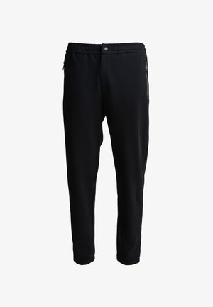 Sorte joggerbukser med elastisk talje, sidelommer med lynlås og tætsiddende ben. Fremstillet af blødt stof med en glat overflade.