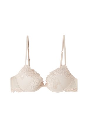 Soutien-gorge beige à bordure en dentelle, avec des bonnets rembourrés, des bretelles ajustables, une base texturée et des bords festonnés sur les bonnets et la bande.