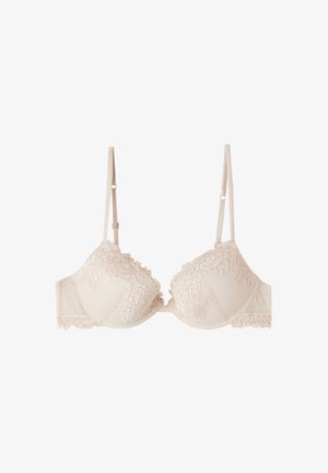 Soutien-gorge beige à bordure en dentelle, avec des bonnets rembourrés, des bretelles ajustables, une base texturée et des bords festonnés sur les bonnets et la bande.