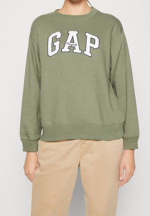 Olijfgroene sweatshirt met geribbelde mouwen en zoom, voorzien van een witte geborduurde 'GAP' logo. Gecombineerd met lichtbeige broek.