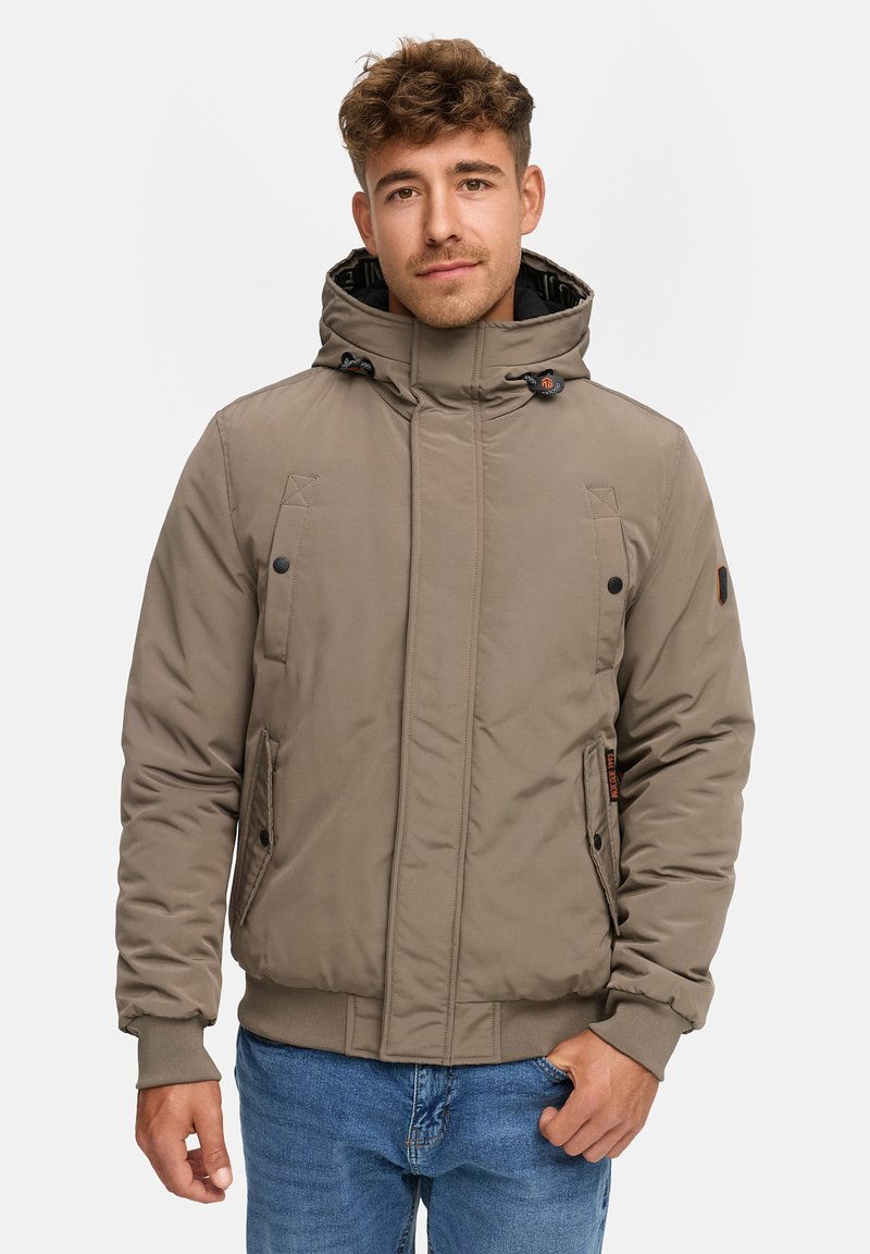 Khaki pufferjakke med justerbar hætte, frontlommer og ribbede manchetter. Har diskrete stikninger og en varm, isoleret tekstur.