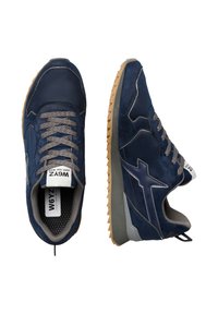 Sneakers sportive blu navy in materiale scamosciato, con lacci grigi testurizzati, suola in gomma color caramello e un distintivo logo sulla parte laterale.