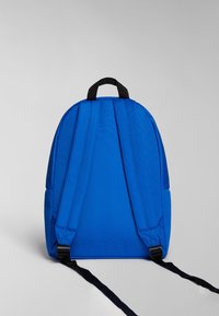 Mochila azul con una tela suave y texturizada, correas ajustables negras y un asa superior. Presenta una forma redondeada y un diseño minimalista.