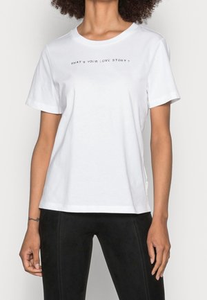 Witte katoenen t-shirt met een ronde hals, korte mouwen en de tekst "WAT IS JOUW LIEFDESVERHAAL?" in het zwart op de borst gedrukt.