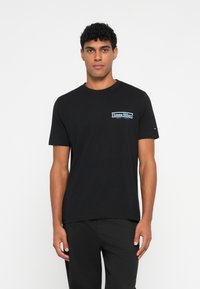 Sort bomulds t-shirt med korte ærmer, som har et blåt og hvidt "Tommy Hilfiger" logo på venstre bryst. Enkel rund hals.