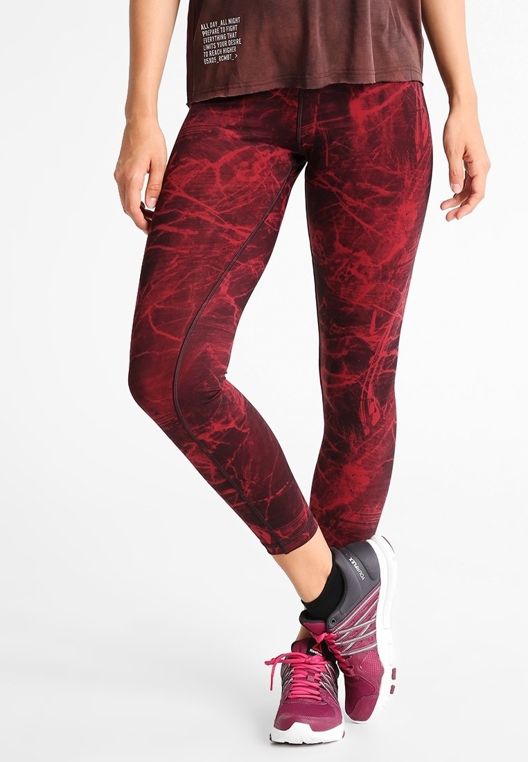 Leggings rossi a fantasia con un design elegante, caratterizzati da una texture marmorizzata, una forma aderente e un tessuto morbido ed elastico. Abbinate a sneakers grigie.