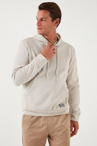 Felpa leggera color beige con tasca a canguro, cappuccio con cordoncino, polsini e orlo a costine. Presenta un piccolo logo etichetta sulla tasca inferiore.