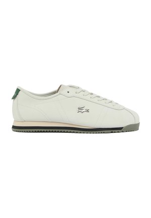 Sneaker in pelle bianca a basso profilo con suola in gomma verde, chiusura frontale con lacci e piccolo logo coccodrillo sul lato.