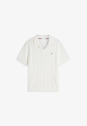 Polo a maniche corte in maglia bianca con texture a coste, colletto aperto e piccolo logo rosso, bianco e blu sul petto sinistro.