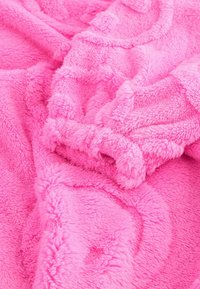 Tissu polaire doux rose vif avec une surface duveteuse et texturée, montré en gros plan sur des plis et des rides.