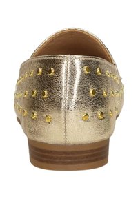 Achteraanzicht van een metallic gouden platte schoen met kleine gouden studs en een lage gestapelde houten hak.