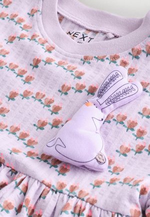 Lavendelfarvet kjole med blomstermønster i brune og lyserøde nuancer, med en blød kanin som pynt. Blødt stof med rynket talje for tekstur.