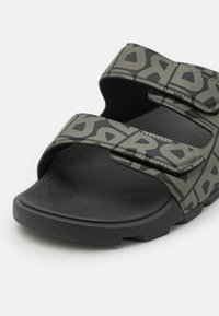Sandales noires et vert olive avec deux sangles réglables arborant un motif audacieux, fabriquées en matériau synthétique et dotées d'une semelle texturée.