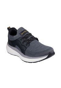 Zapatilla deportiva Skechers en malla gris oscuro con acentos en negro, que cuenta con una suela blanca acolchada y cordones elásticos para un ajuste seguro.