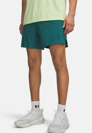 Groene sportieve korte broek met een gestructureerd patroon, voorzien van een klein zwart logo. Gecombineerd met witte sneakers en geribbelde witte enkelsokken.