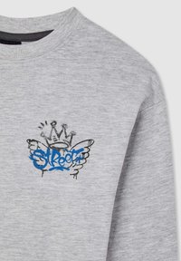 Jasnoszary sweatshirt z graffiti-stylowym wzorem, na którym widnieje niebieski napis "Street", czarna korona oraz elementy ze skrzydłami na górnej części przedniej klatki piersiowej.