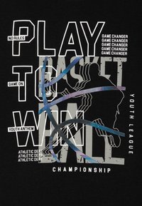 Camiseta negra con texto en blanco y gris en negrita: “JUEGA PARA GANAR” con gráficos de baloncesto, líneas y tamaños de fuente variados, enfatizando temas atléticos.