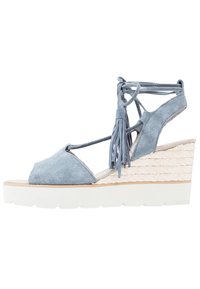 Blue suede wedge sandal with fringe detailing, open toe design, and textured woven platform. White rubber sole provides stability.