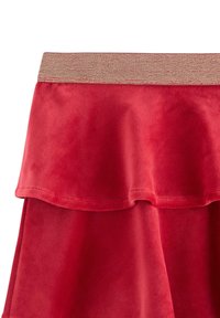 Gonna rossa con un design a strati, caratterizzata da una texture morbida e un ampio cinturino elastico luccicante.