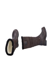 Botas de cuero marrón hasta la rodilla con un suave forro de lana crema y suelas de goma texturizadas. Cuenta con una cremallera decorativa y un acento de logo de metal.