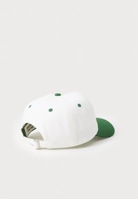 Hvit baseballcaps med grønn skygge; har broderte ventilasjonsåpninger og justerbar stropp bak. Laget av bomull med en glatt tekstur.