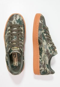 Sneakers i kamouflagemönster med grön ovandel, gummisula i beige och texturerade snören. Har en gyllene logotyp på tungan.