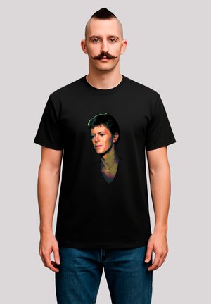 Black cotton t-shirt featuring a colorful graphic print of a face. The design includes a prominent neckline and a subtle cross accessory.