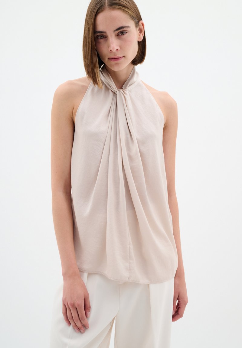 Bezramenný halter top z jemného béžového materiálu, s nařaseným výstřihem a volnou siluetou s měkkou texturou a splývavým designem.