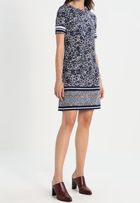 Robe à manches courtes bleu marine avec un motif floral, des rayures blanches contrastantes sur les manches et une bande à motifs horizontale au niveau de l'ourlet.