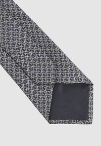 Marinblå slips med ett geometriskt mönster med vita konturer; textil med struktur och en slät undersida; spetsig spets och rena kanter.