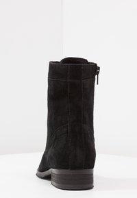 Stivaletto alla caviglia in suede nero con tacco basso, dotato di zip laterale e design essenziale. Texture morbida con dettagli di cucitura discreti.