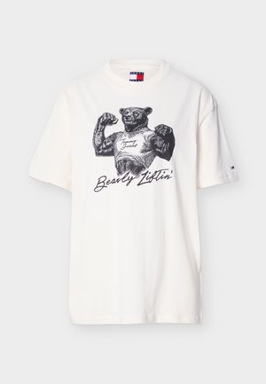 Bela majica s kratkimi rokavi z mišičastim medvedom, ki kaže mišice in nosi majico brez rokavov z napisom "Tommy Jeans" ter besedilom "Bearly Liftin'" spodaj.