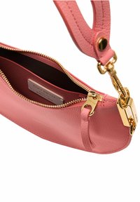 Różowa skórzana torebka z zapięciem i zapięciem w kolorze złotym. Posiada teksturowane wykończenie i jedną rączkę do noszenia. Widoczna wewnętrzna metka.