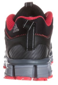 Černá sportovní bota s červeným síťovaným svrškem, texturovanou syntetickou patou a šedou podrážkou. Obsahuje poutko a kontrastní švy.