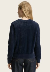 Dunkelblaues, kuscheliges Sweatshirt mit Rundhalsausschnitt, langen Ärmeln und geripptem Saum, das eine weiche Textur und eine entspannte Passform bietet.