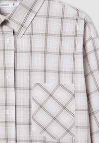 Camicia a quadri con design a plaids beige e marrone, dotata di colletto a camicia, bottoni bianchi e taschino sul petto con linee diagonali.