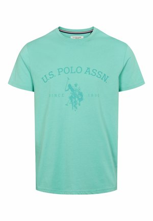 Svijetlo plava pamučna majica kratkih rukava. Ima okrugli izrez i otisnutu U.S. Polo Assn. matricu s grafikom igrača poloa.