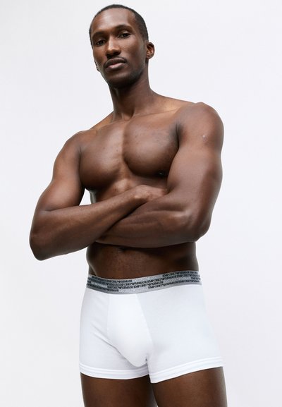 Fehér boxeralsó fekete Emporio Armani derékpánttal. Az anyag lágy és testhezálló, kiemelve a modell fizikumát.