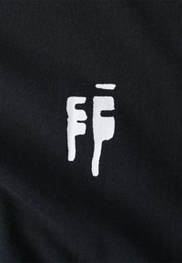 Black fabric with a soft texture features a white graphic logo design in the shape of stylized letters "FF" and drips beneath.
